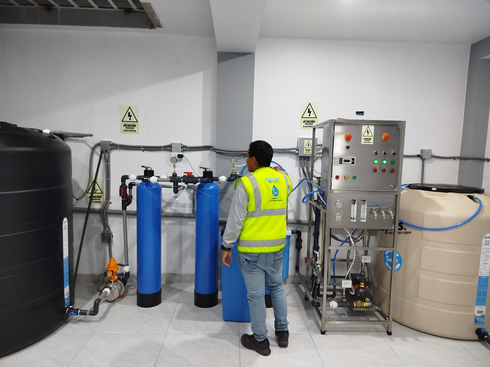 Técnico de Yacu Import junto a filtros de tratamiento de agua, tuberías y tablero de control